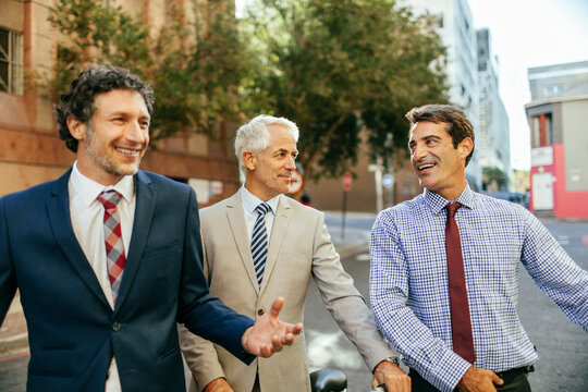 Three businessmen talking on the street and walking to work