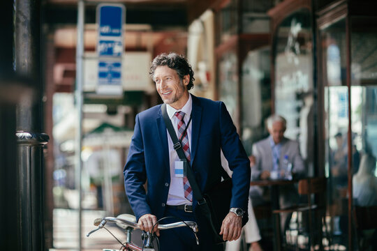 Happy middle aged businessman going to work with a bicycle in the city