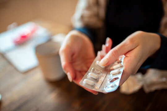 Close up of a young woman taking pills for her cold at home