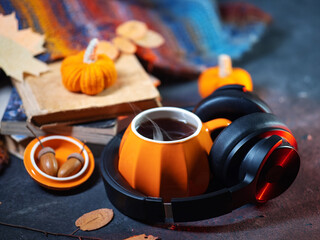 Wireless headphones with books on the table. Cozy environment for learning, audiobook concept. A cup of hot tea, autumn mood.