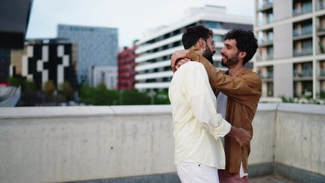 Two gay sweethearts joyfully dance hand in hand, truly living in present and basking in contagious allure of their shared happiness. LGBT male couple hug and kiss during romantic dating. Slow motion