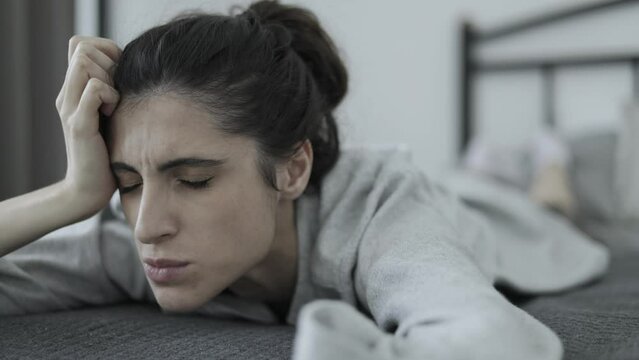 Woman with nervous tic and mental disorder lying on bed at home