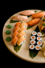 Assorted sushi rolls on a round wooden board top view