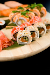 Assorted sushi rolls on a round wooden board, side view