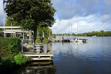 Bootssteg mit Segelboot, Liegestuhl und Deckchair im Herbst bei Sonnenschein im Alsterpark am...