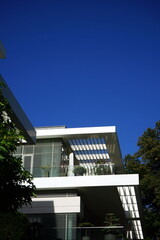 Modernes Wohnhaus in Schneeweiß mit Penthouse und Dachterrasse vor blauem Himmel im Sonnenschein...