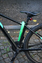 Modernes Mountainbike in Schwarz mit grün ummanteltem Fahrradschloss bei Regenwetter mit Regentropfen auf dem Sattel im Stadtteil Harvestehude an der Alster in der Hansestadt Hamburg