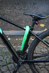 Modernes Mountainbike in Schwarz mit grün ummanteltem Fahrradschloss bei Regenwetter mit Regentropfen auf dem Sattel im Stadtteil Harvestehude an der Alster in der Hansestadt Hamburg