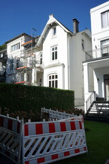 Weiße Fassade einer sanierten alten Villa und anderer Wohnhäuser vor blauem Himmel im...