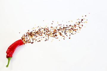 hot red chili pepper with chili flakes burst in white background as food background,top view with copy space - obrazy, fototapety, plakaty