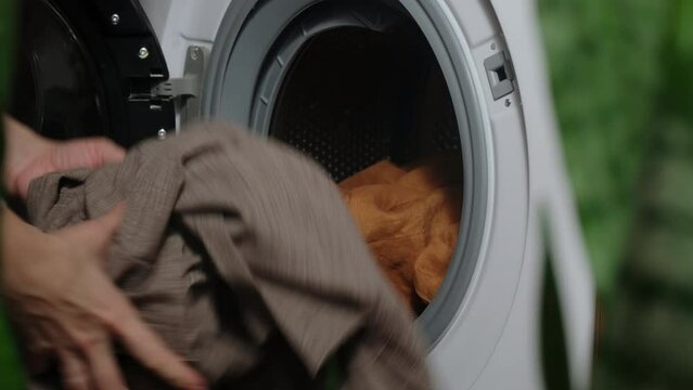 Housewife doing laundry using washing machine.