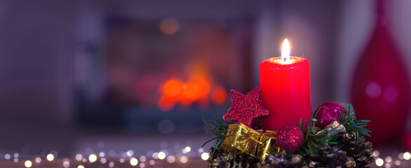 Glowing Advent candle and fireplace in blurred background