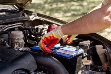 car mechanic repairs a car. A mechanic removes a car battery