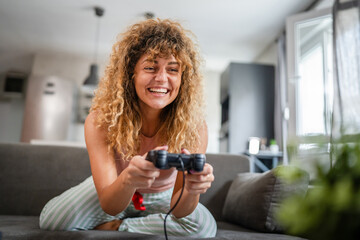 young woman play console video games hold joystick at home happy smile