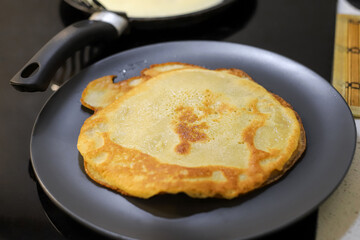 Making bliny at home. Traditional tasty thin pancakes covered with butter. Photo with selective focus