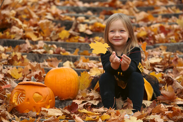 little girl with halloween pumpkin in the autumn park 