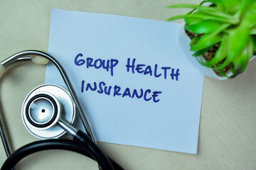 Concept of Group Health Insurance write on sticky notes with stethoscope isolated on Wooden Table.