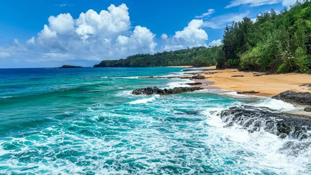 Low-flying drone view of a Hawaiian beach with blue water, golden sand and black volcanic rock, with gentle waves washing up on the beach