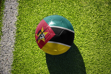 football ball with the flag of mozambique on the green field near the white line - obrazy, fototapety, plakaty