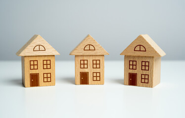 Three wooden toy houses. Offers on real estate market. Mortgage. Valuation of residential buildings. Realtor services. Buying and selling. Find most suitable housing options.