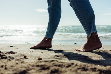 Close-up of female bare feet on the sand by the seashore.