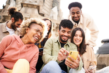 Group of people watching video on the mobile phone. Smiling friends using phone and laughing. Youth culture and technology concept. High quality photo