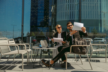 Two business partners working with documents sitting outside of office on cafe terrace