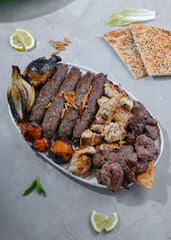 assorted kebabs grilled, Grilled chicken pieces, Grilled onions and tomatoes, Bread on the table