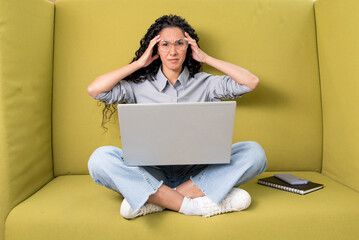 Frustrated sad puzzled Hispanic brunette girl, freelancer or designer, got a negative result, failed the project, looks desperately at camera, holds her hands on her head, have stressed situation