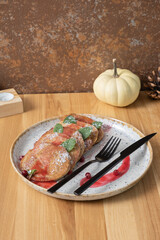 A plate of pumpkin pancakes with cutlery on wooden background top view, flat lay