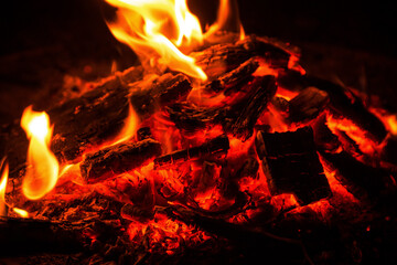 Hot red coals in bonfire close up at night