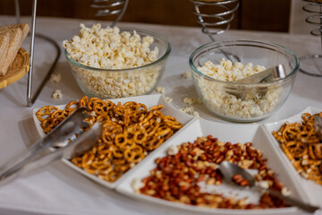 bowls and plates of various snacks including pretzels and popcorn