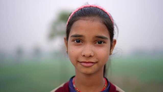 Happy Indian girl looking at camera and smiling in outdoor setting in the Indian countryside. 