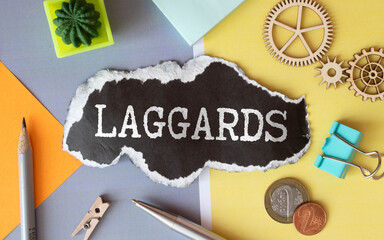 Pen and brown card with Laggards on wooden background.
