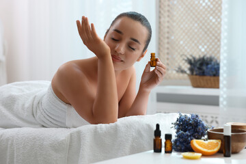 Young woman with bottle of essential oil in spa salon
