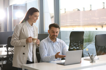 Colleagues working on laptop at desk in office