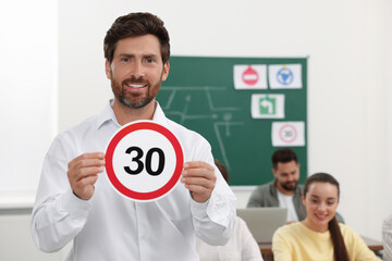 Teacher showing Speed Limit road sign during lesson in driving school. Space for text
