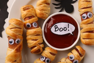 Tasty sausage mummies for Halloween party on plate, top view