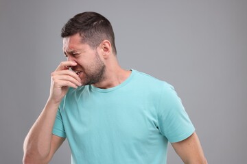 Allergy symptom. Man sneezing on light grey background
