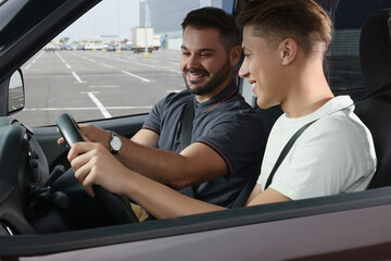 Driving school. Happy student during lesson with driving instructor in car at parking lot