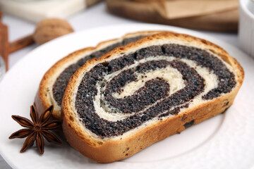 Slices of poppy seed roll and anise star on plate, closeup. Tasty cake