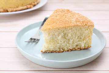 Piece of tasty sponge cake on white wooden table, closeup