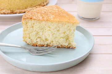 Piece of tasty sponge cake on white wooden table, closeup