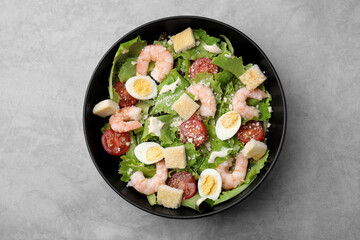 Delicious Caesar salad with shrimps on grey table, top view