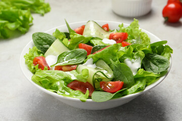 Delicious vegetable salad on light grey table, closeup
