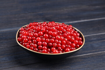 Ripe red currants in bowl on wooden rustic table