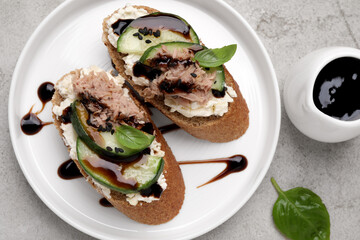 Delicious bruschettas with balsamic vinegar and toppings on light textured table, flat lay