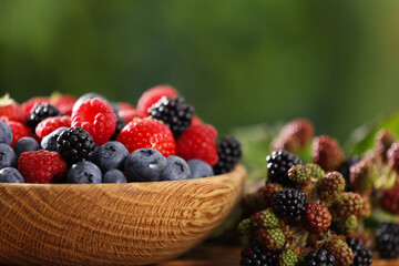 Bowl with different fresh berries on table outdoors, closeup