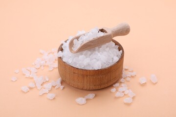 Bowl and scoop with sea salt on beige background, closeup