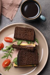 Delicious sandwiches with boiled sausage, tomato, cheese and arugula on grey table, flat lay